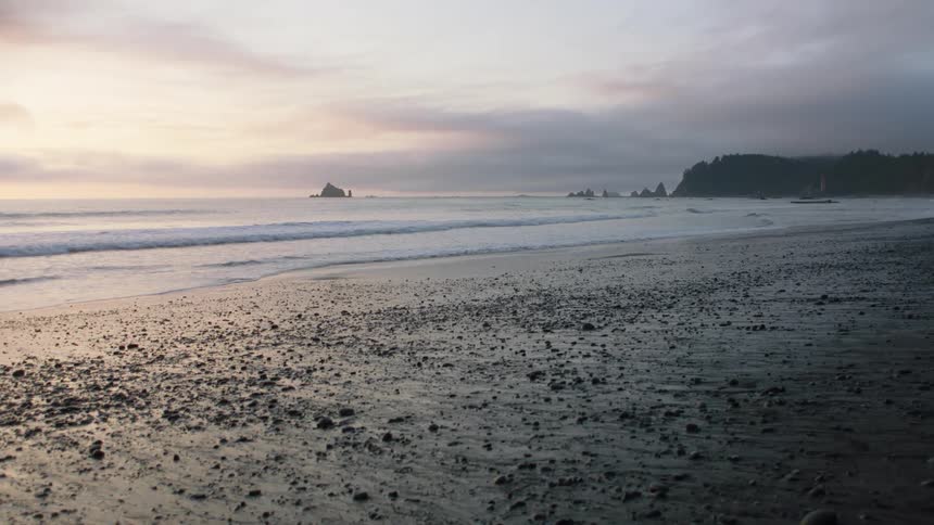Waves wash upon a rocky shoreline underneath an overcast sky