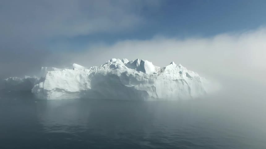 Glaciers with snow and ice in a body of water with the sky and clouds in the background