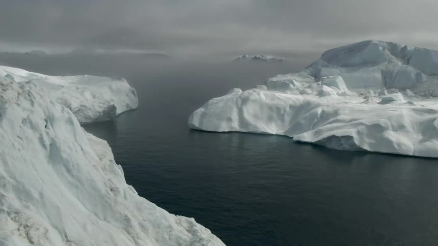 Glaciers with snow and ice in a body of water with the sky and clouds in the background