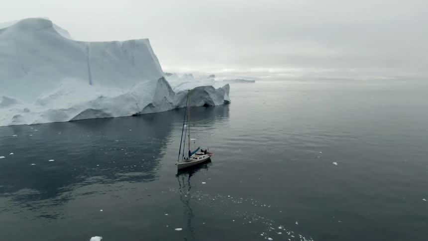Fishing boat in the middle of the ocean besides an iceberg