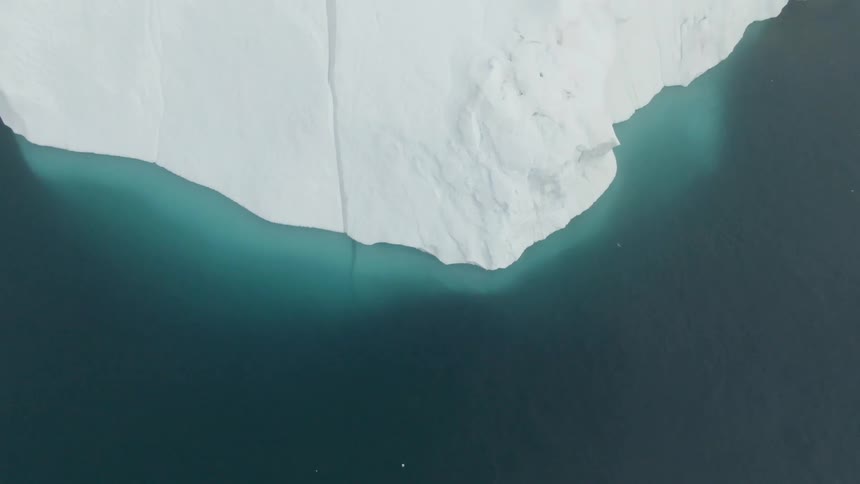 Blue ocean water flowing around a snowy glacier in nature