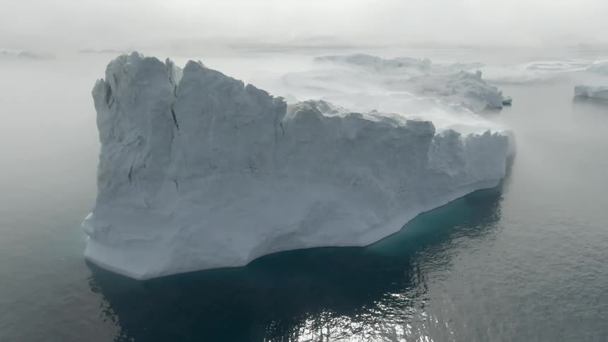 A large snow covered iceberg sits in the ocean