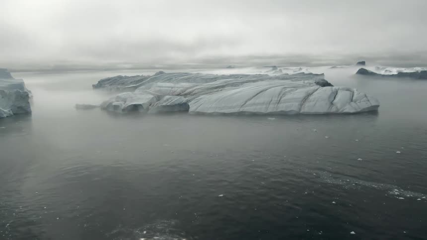 Glaciers with snow and ice in a body of water with the sky and clouds in the background