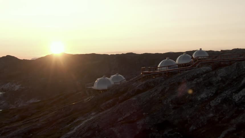 A cliff with domes with the sunset the sky and clouds in the background