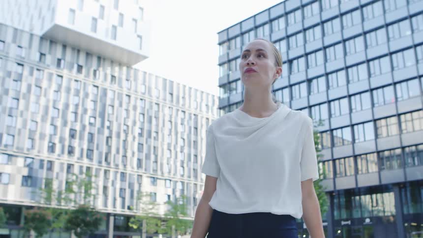 A woman walks through a plaza between downtown buildings