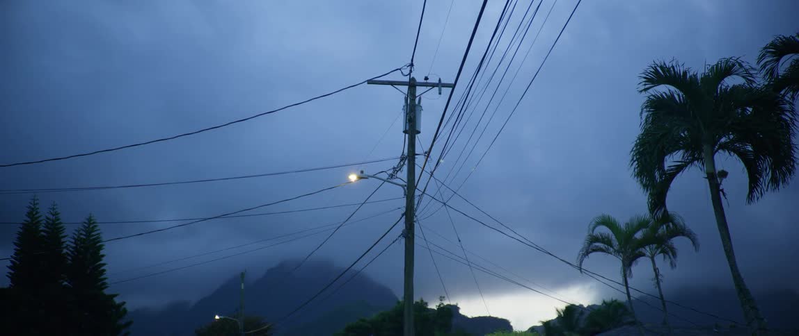 Power lines hanging from an utility pole under the clouds