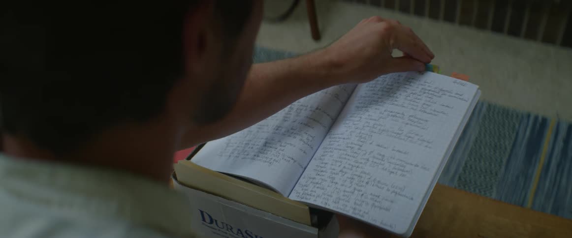 A man is paging through a notebook with writing on each page