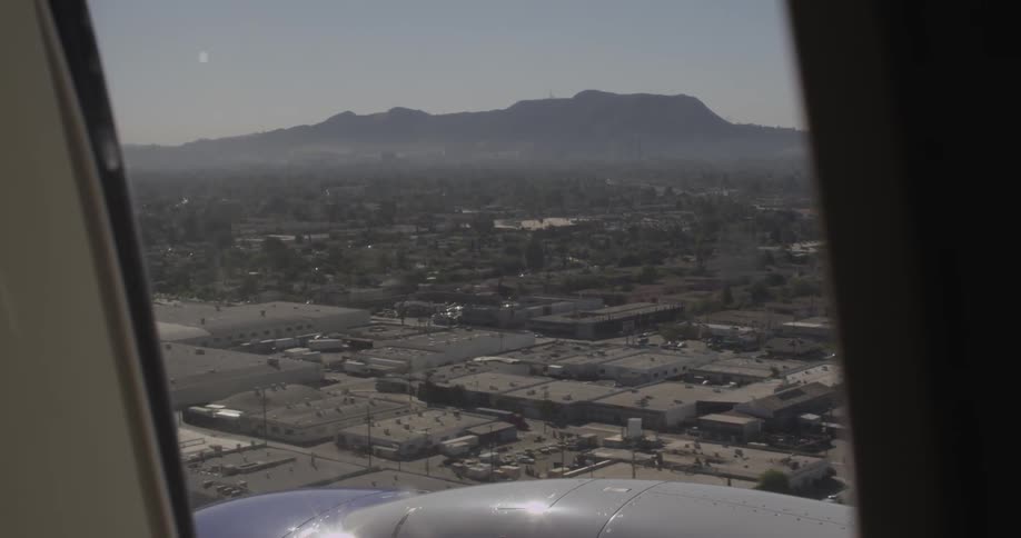 The view from a plane window shows buildings below
