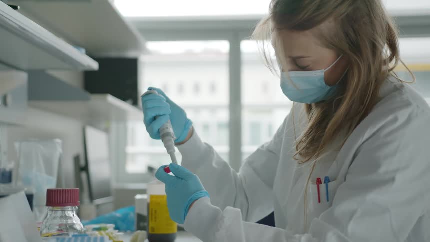 Laboratory technician adds drops to container then closes it