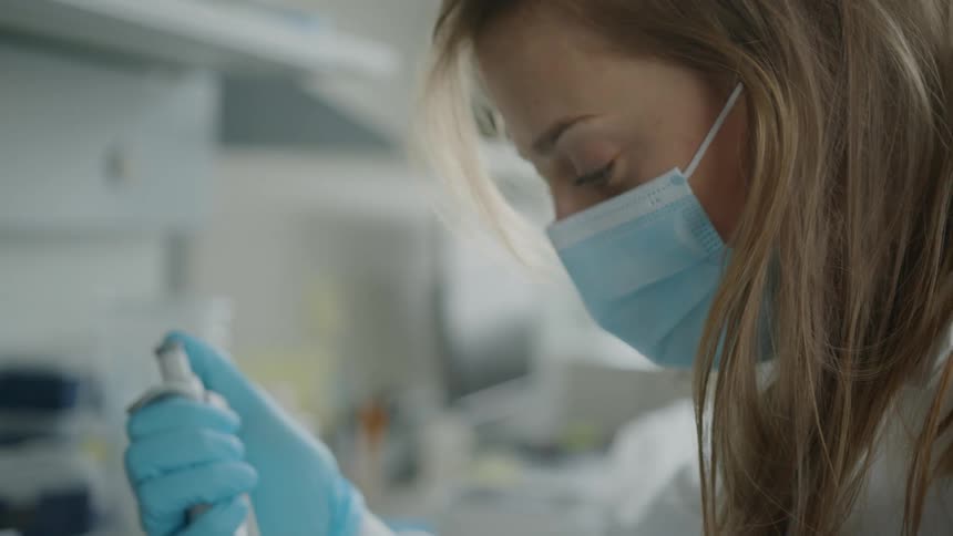 Woman using a syringe in a lab