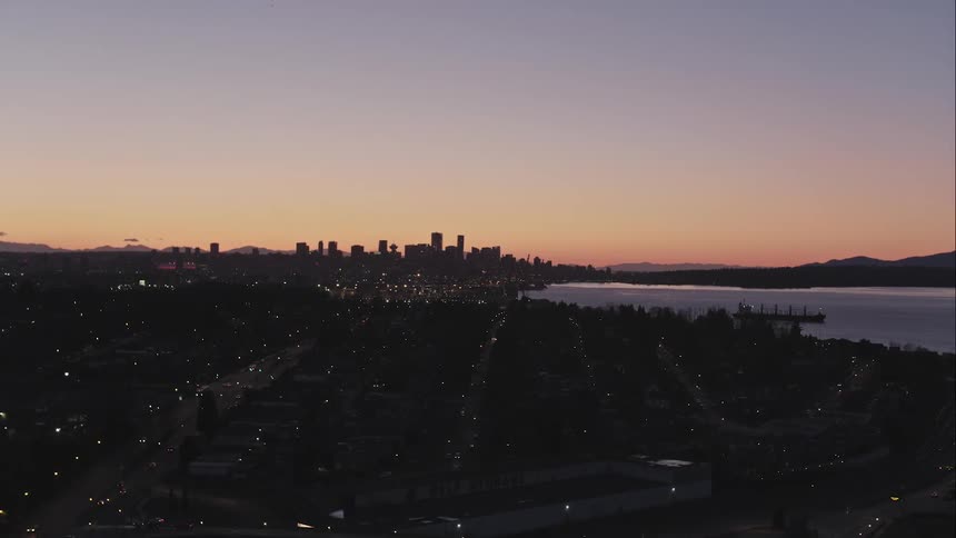 Distant Vancouver city skyline glows in aerial view at dusk