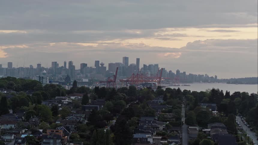 Aerial reveals downtown Vancouver and harbour behind foreground neighbourhood
