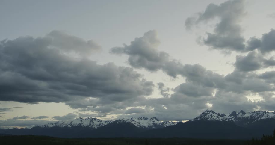 Clouds pass over rugged mountains