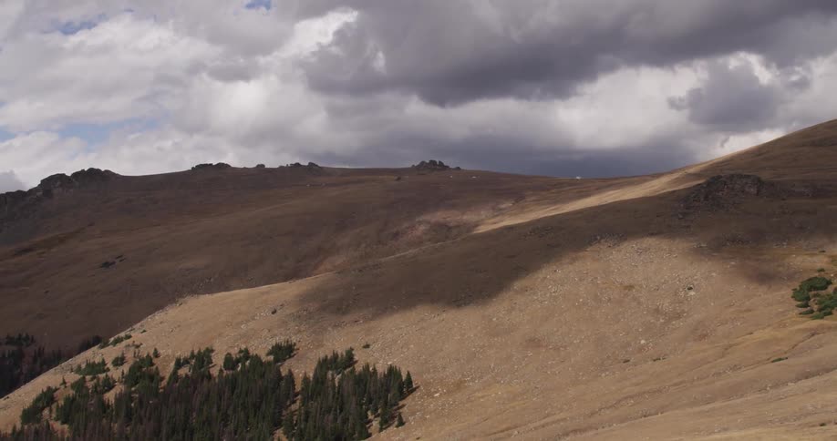 A large hillside has heavy clouds above