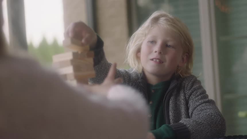A young girl plays jenga with her mother