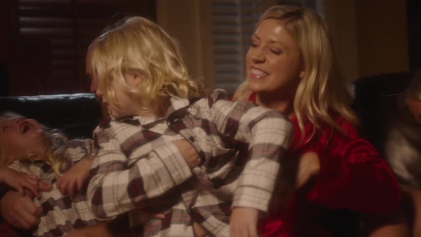 A man and woman and three children sitting on a couch in a room laughing