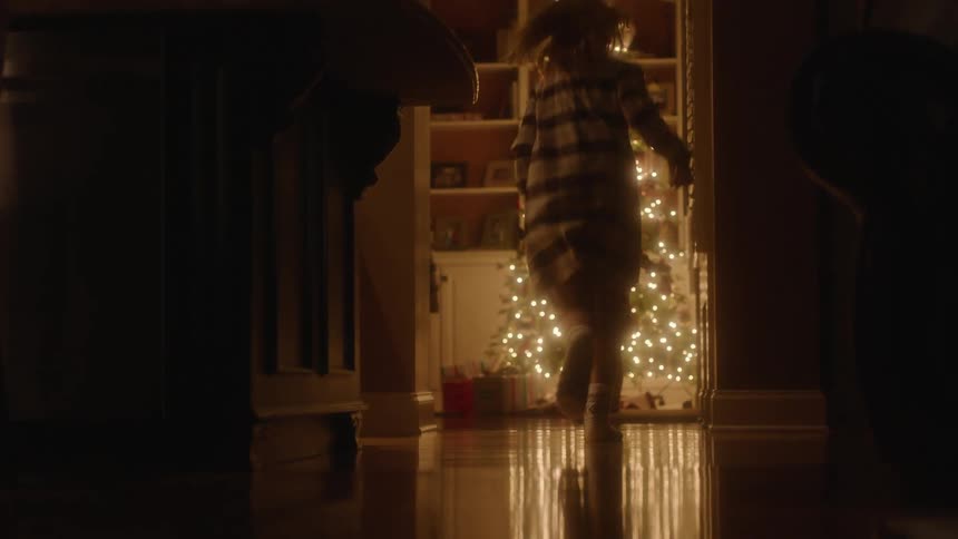 Kids are excitedly running to see the presents under the christmas tree at night