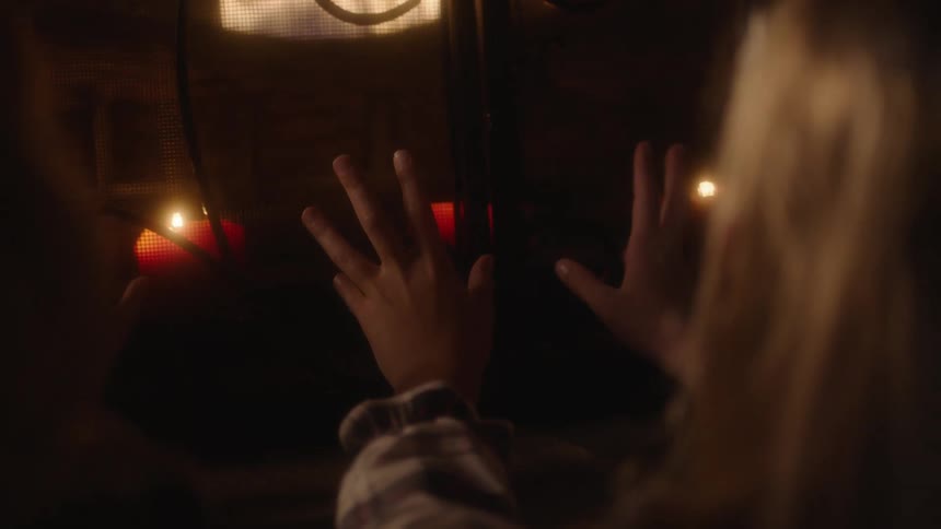 Girl sitting in front of a fire place warming her hands