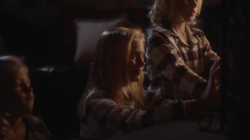 Three blonde sisters cluster around heating warming themselves
