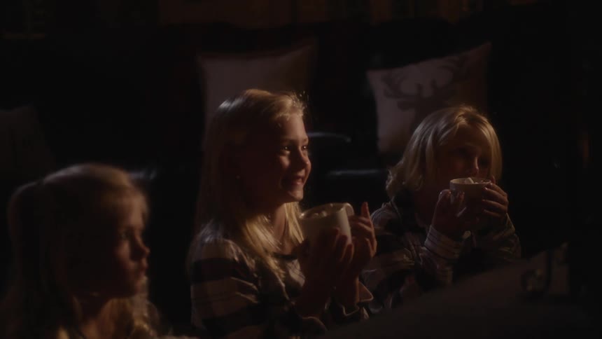 Three sisters sit smiling while watching show