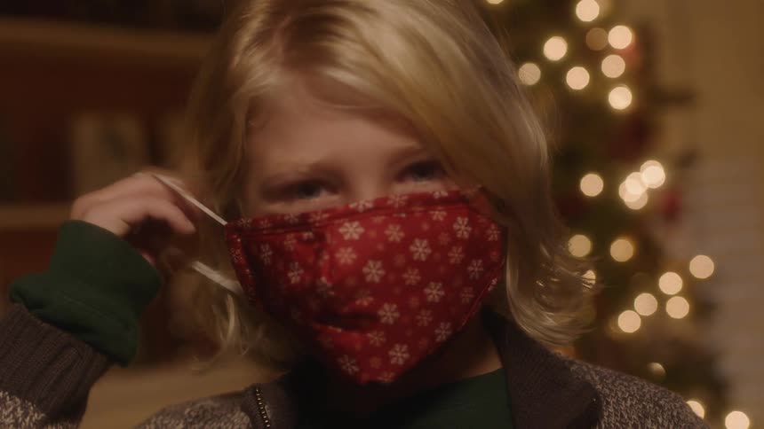 Blond woman pulls a covid mask up and over her face then puts the elastic ear loop over her ear