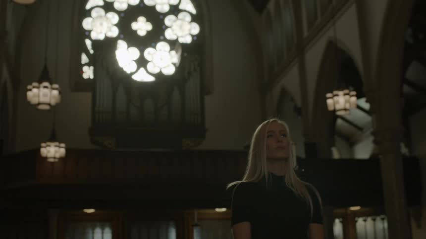 A woman stands in a church looking up