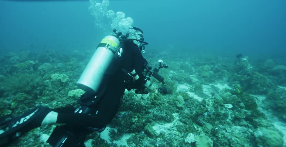 People scuba diving with cameras underwater with bubbles