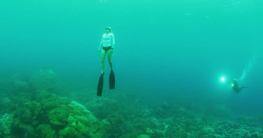 freediver swimming to surface under water of scuba diver