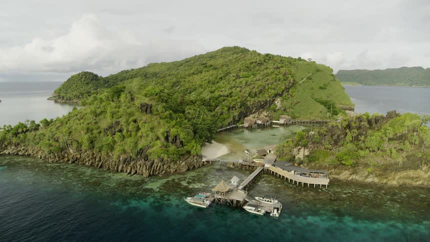 A dock with boats and a hut near the coast of an island with the sky and clouds in the background