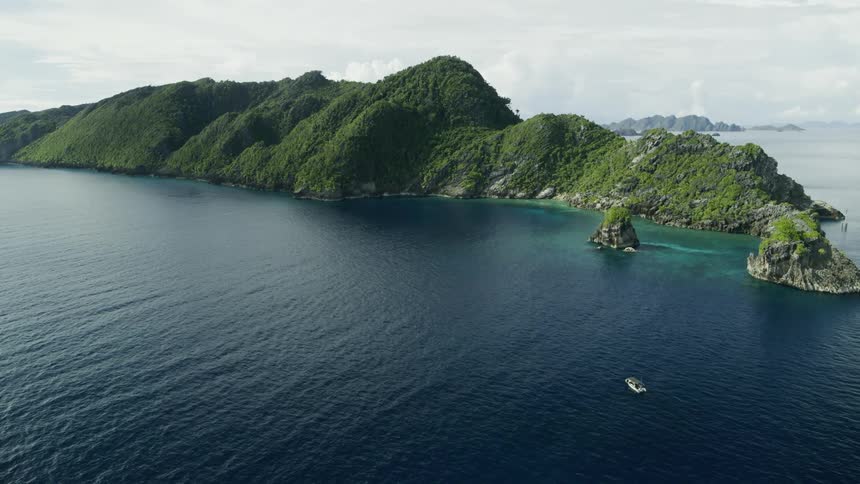 A white sailboat heads toward a cluster of islands in clear blue water