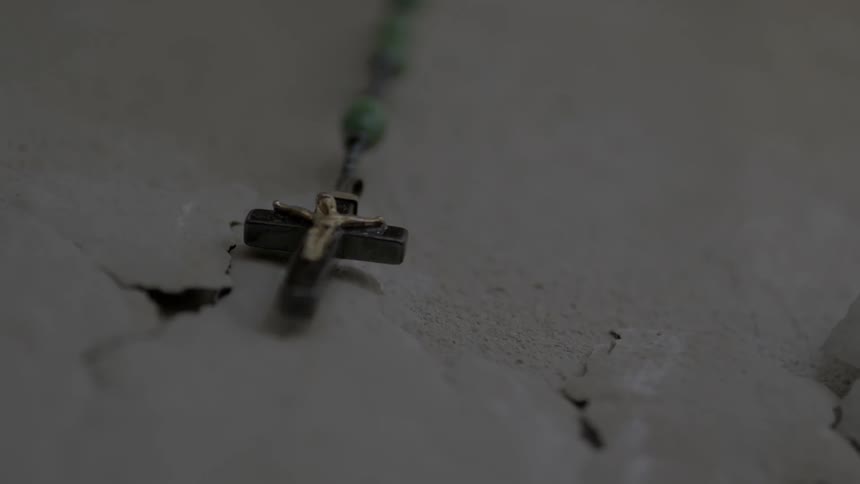 The cross from a rosary bouncing off a wall
