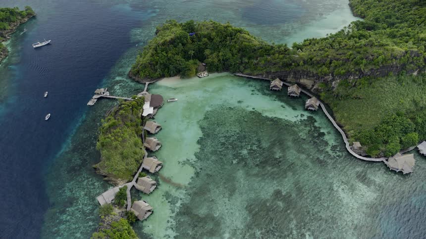 An aerial view of an inlet with houses on the water ocean in the background and boats in the water