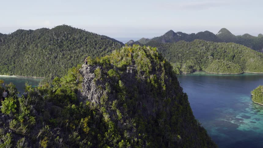 A cliff with trees near a body of water with the sky and clouds in the background