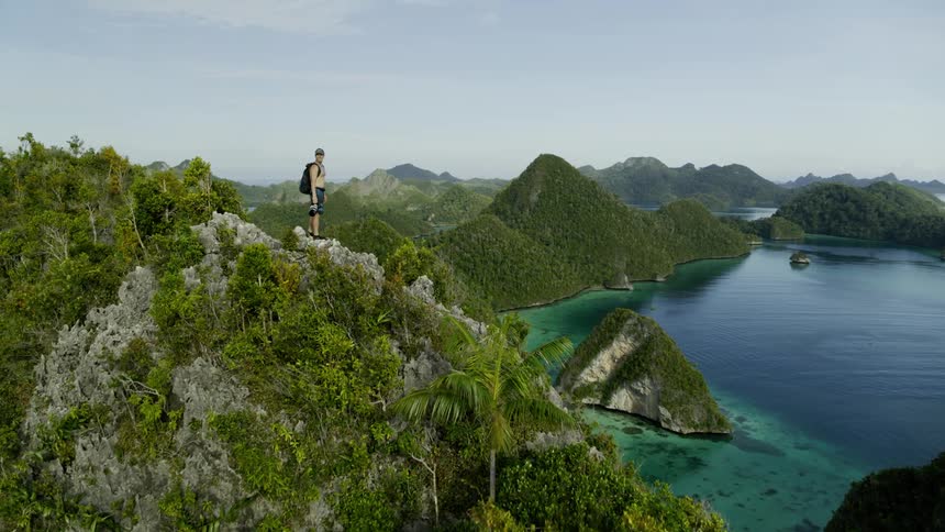 Man climbing large sea cliff on an island surrounded by ocean