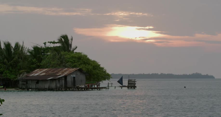 An old building on a small dock on the coast under a cloudy evening sky