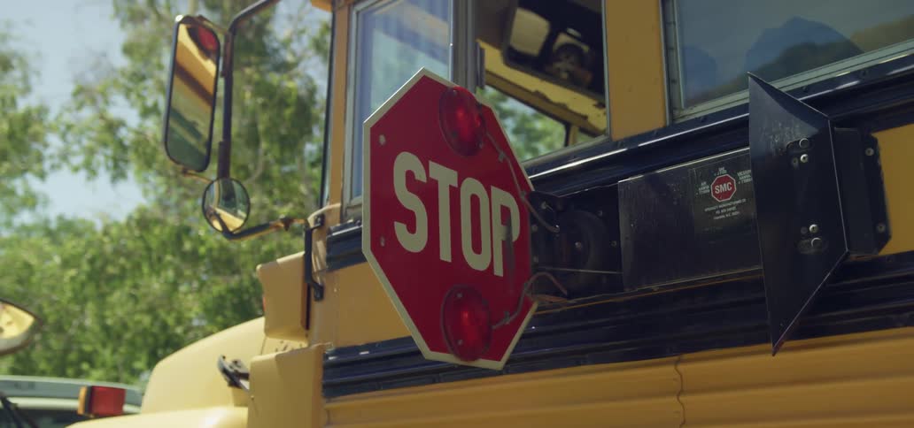 A school bus driver sits in a bus with the bus stop sign out