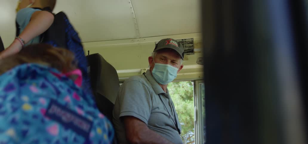 A school bus driver watches kids climbing on to the school bus