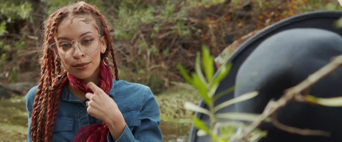Young woman wearing glasses looks at the camera while handling the red scarf around her neck