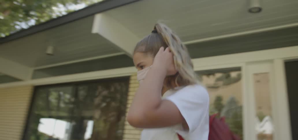 Young girl leaving her house putting on a face mask