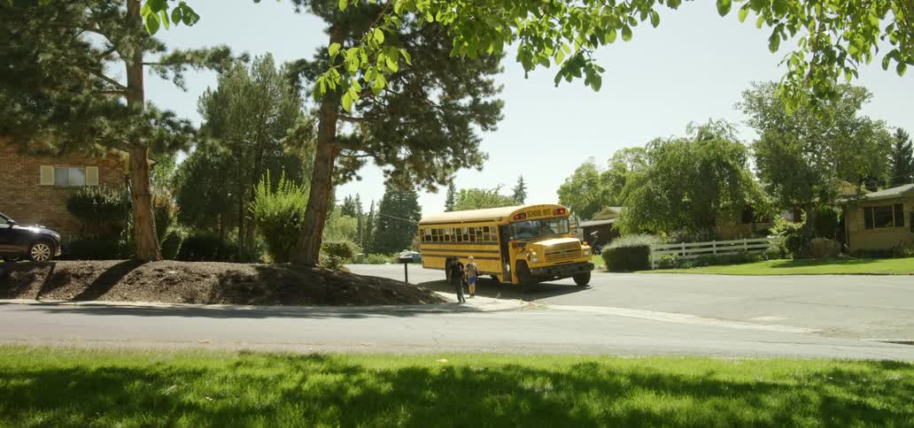 Children exit a school bus on a street in a neighborhood during the day