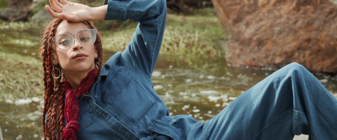 Female model lying down next to a river posing at the camera