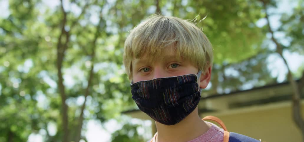 Blonde boy with a black mask looks at the camera