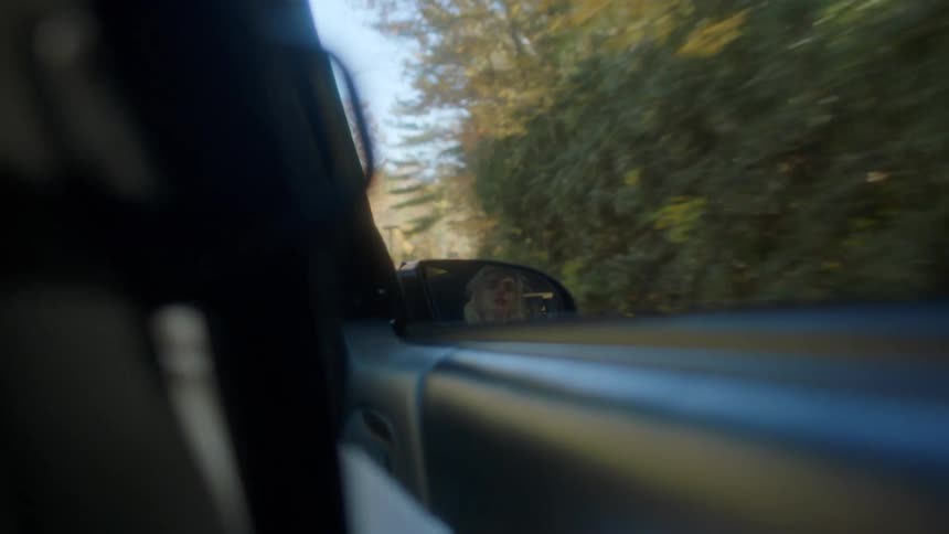 Reflection of a woman sleeping in the back of a car waking up