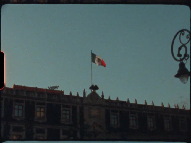 A mexican flag flies above a government building