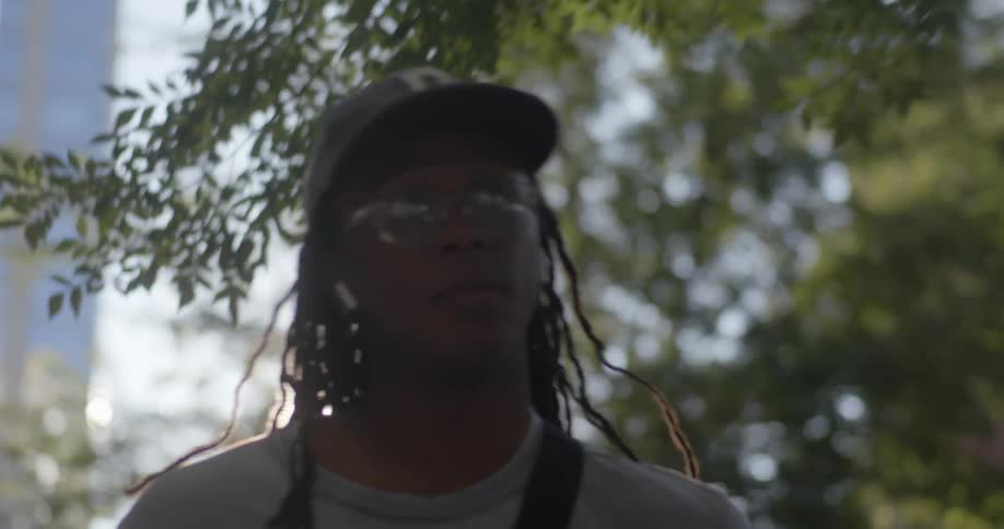 Man wearing earbuds walking on sidewalk in a city looking around