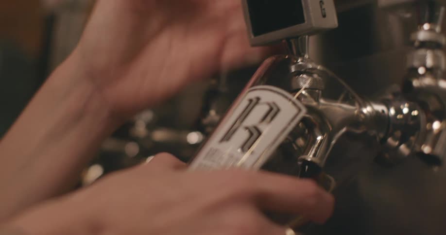 A cup is rinsed in water then brought up to a tap and beer is dispensed