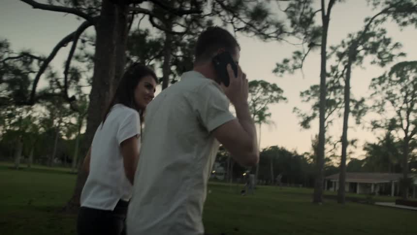 Man and woman walking towards a house together while man talks on his cellphone