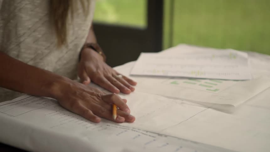 Woman laying out plans and reviewing paperwork on a table indoors