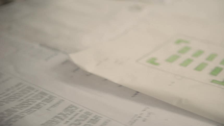 A person is writing notes on blueprints