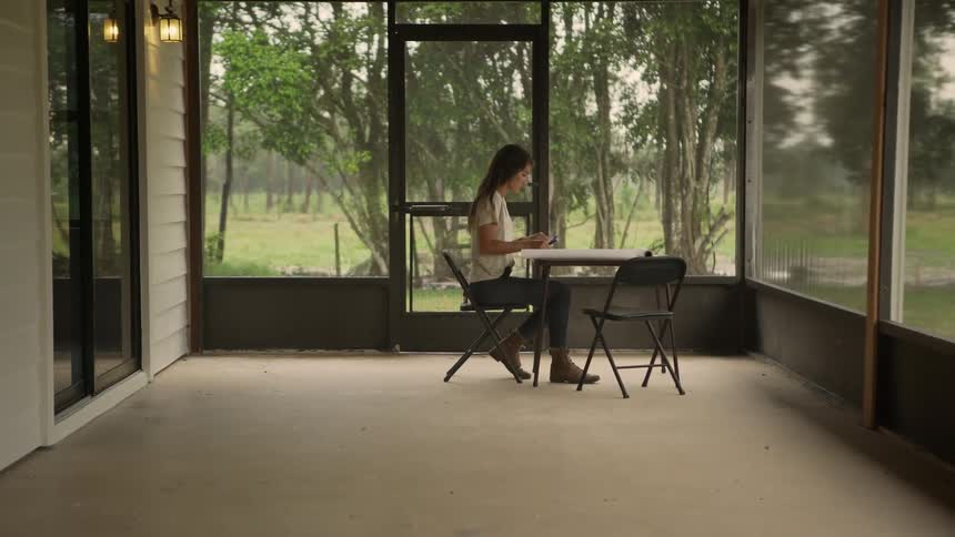 A woman opens up papers on a table in a sunroom